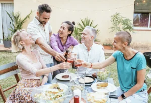 happy people sitting outside toasting wine