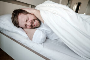 man in bed trying to sleep and being stressed out