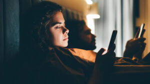 couple lying in bed with smartphones